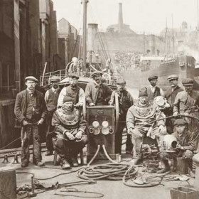 Divers in North Dock,  c 1915Front row from the left Mr Stanbridge (standing), diver Alf Knapp, diver Mr Beer and  Tommy Phillips ( Trimmer )(standing)Ship behind Mr Beer, Londonderry's "Newtonards"